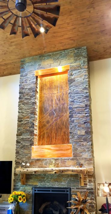 Rustic stone fireplace with wooden mantle and water feature.
