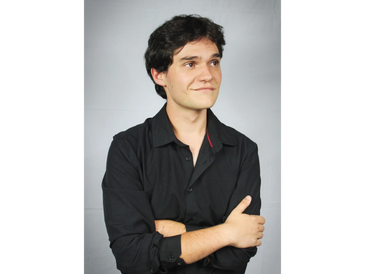Man in black shirt with arms crossed, looking to the side.