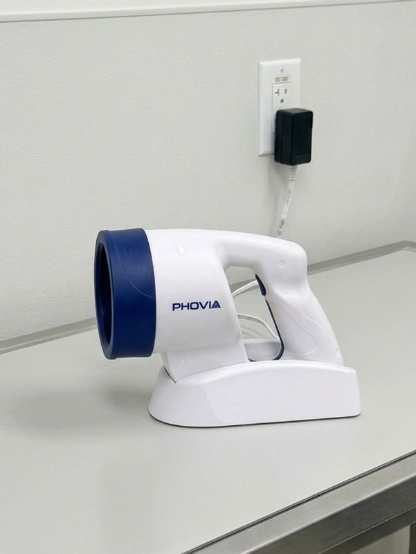 White and blue handheld device labeled Phovia on a table.