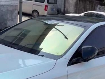 White car with reflective windshield showing building and streetlight.