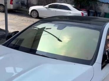 White car with a reflective windshield showing a streetlight.