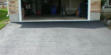 Newly constructed asphalt ramp leading from a driveway to a garage entrance.