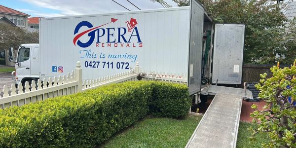 A moving truck with a ramp parked outside a house for removal services.