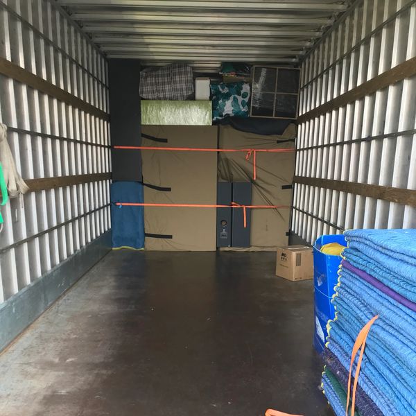 Packed moving truck with secured furniture and blankets.