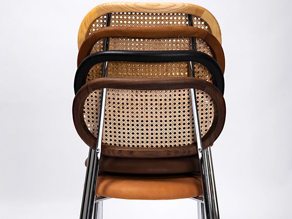 Stacked chairs with woven backs in different wood finishes.