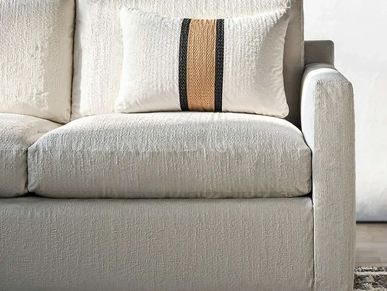 Close-up of a beige textured sofa with a decorative pillow featuring black and brown stripes.