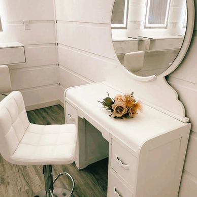 Elegant white vanity table with mirror and cushioned chair.