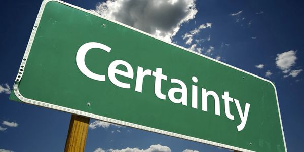Green road sign with the word 'Certainty' against a blue sky.
