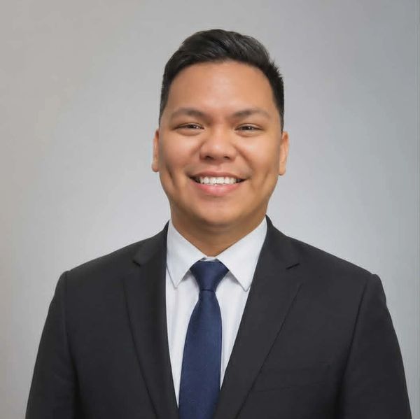 Smiling man in a suit and tie against a plain background.