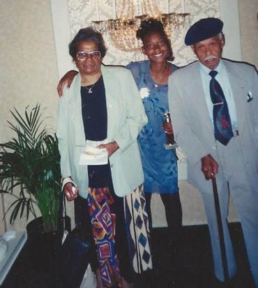 Three generations posing together indoors, smiling warmly.
