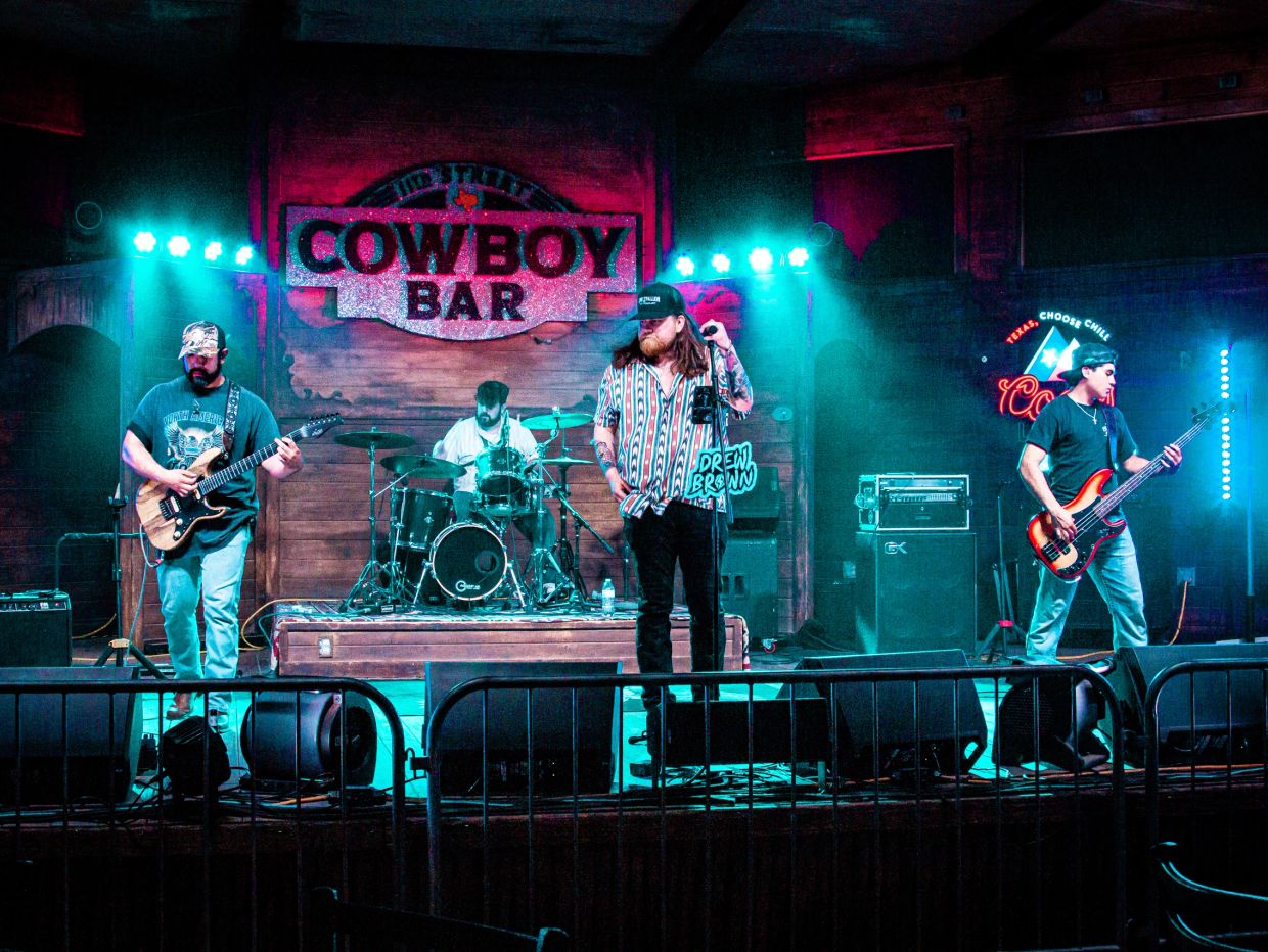 Band performing live at Cowboy Bar with bright stage lights.