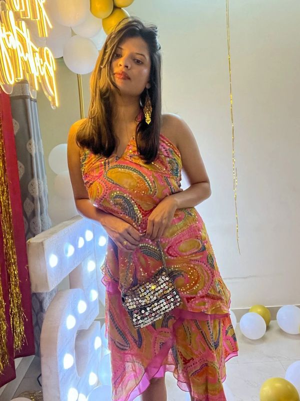 Woman in a colorful dress holding a sequin purse.