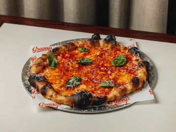 Burnt crust pizza with basil leaves.