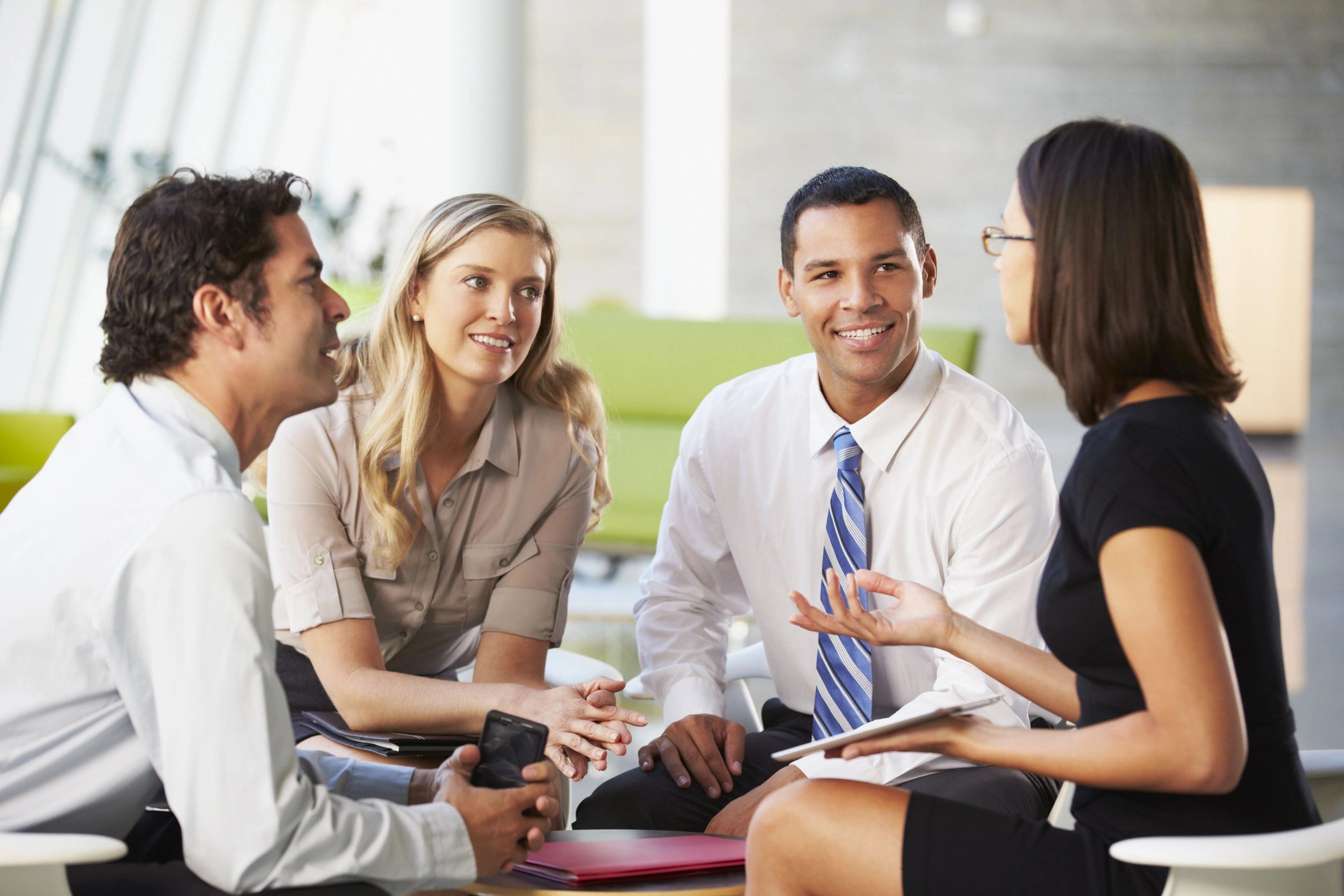 Four professionals engaging in a lively business discussion in a modern office.