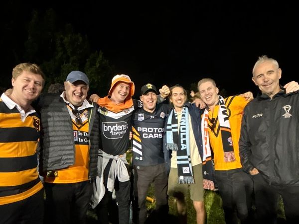 Group of men in sports jerseys celebrating outdoors at night.