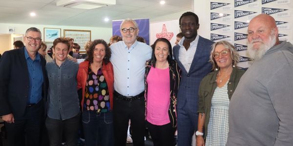 A diverse group of eight people posing together indoors, smiling.