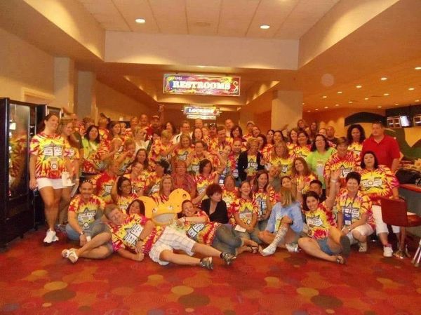Large group of people in matching tie-dye shirts posing indoors.