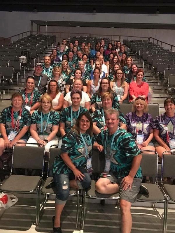 Group photo of people wearing matching tie-dye shirts in an auditorium.