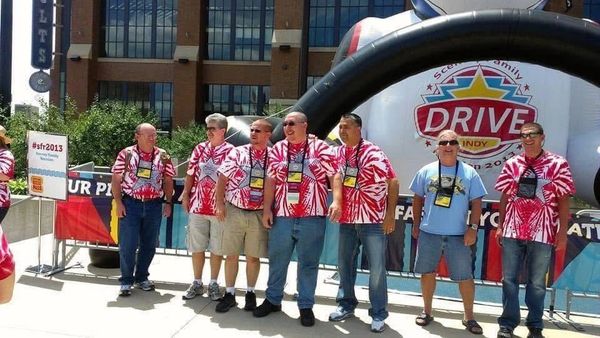 Group of people wearing red tie-dye shirts at an outdoor event.