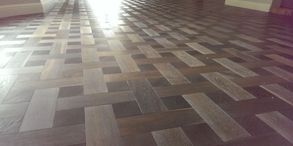Geometric patterned wooden floor with varied shades of brown.