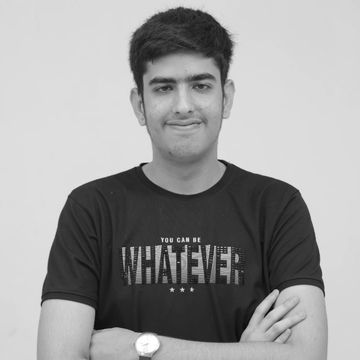 Young man in black t-shirt with arms crossed, smiling slightly.