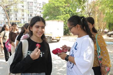 Girls exchanging flowers outdoors, smiling and enjoying the moment.
