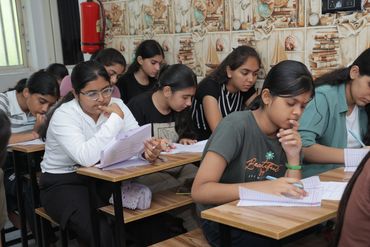 Students intensely focused on writing and reviewing papers in a classroom.