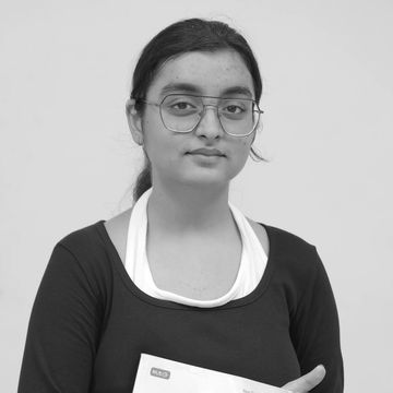 Young woman holding a mathematics foundation course book, standing against a light green background.