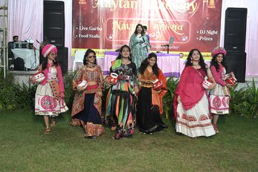 Group of women in traditional attire performing Garba dance outdoors.