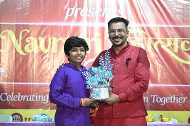 A young boy and man in traditional attire holding a decorated gift at a celebration.