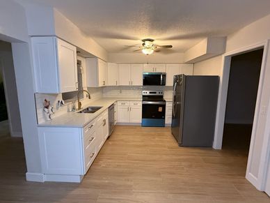 Modern kitchen with white cabinets and stainless steel appliances.