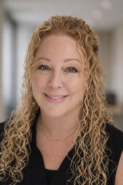 Smiling woman with curly blonde hair in a professional setting.