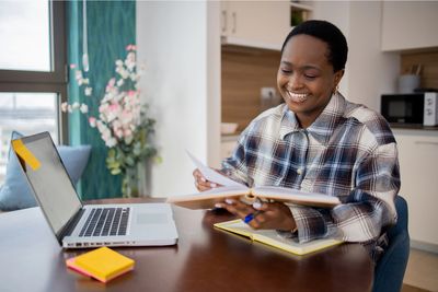 Woman sitting at laptop with note book