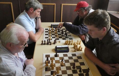 Vier Männer spielen Schach an zwei Brettern.