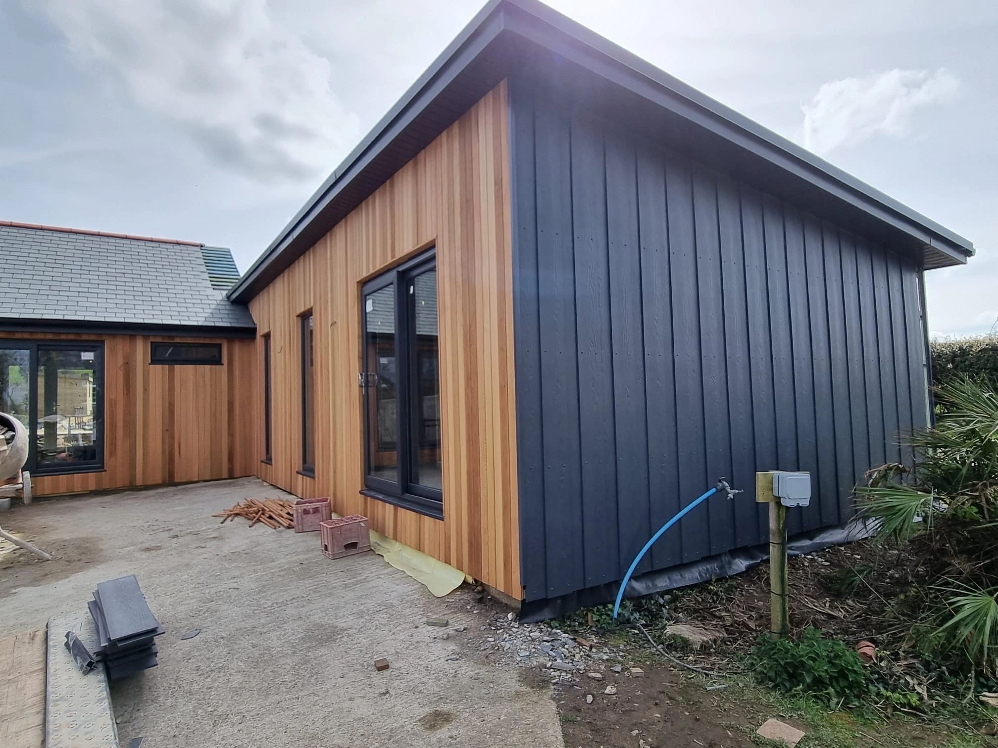 Modern house with wood and dark panel siding under a cloudy sky.