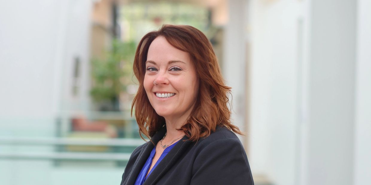 Professional woman smiling confidently in a modern office setting.