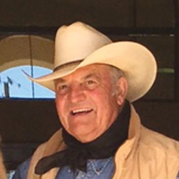 Smiling man wearing a white cowboy hat.