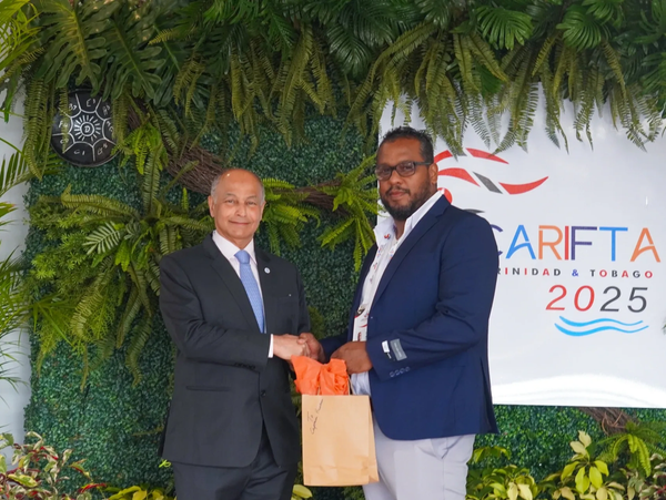 Two men shaking hands in front of a CARIFTA 2025 Trinidad & Tobago banner.