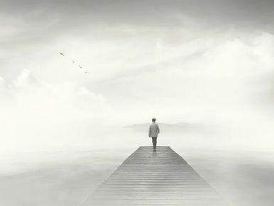 Person stands alone on a foggy pier.
