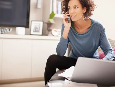 Woman talking on phone while working on laptop.
