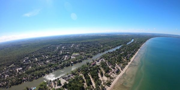Aerial view of a river meeting a long beach under a clear blue sky.