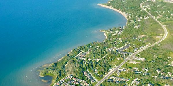 Aerial view of a coastal town with houses and greenery along the shoreline.