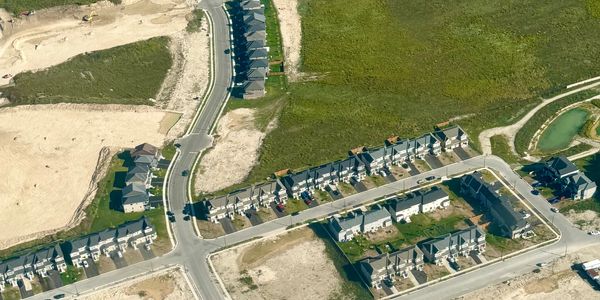 Aerial view of a suburban neighborhood with houses and empty plots.