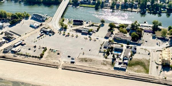 Aerial view of a riverside town with a large parking lot and a bridge.