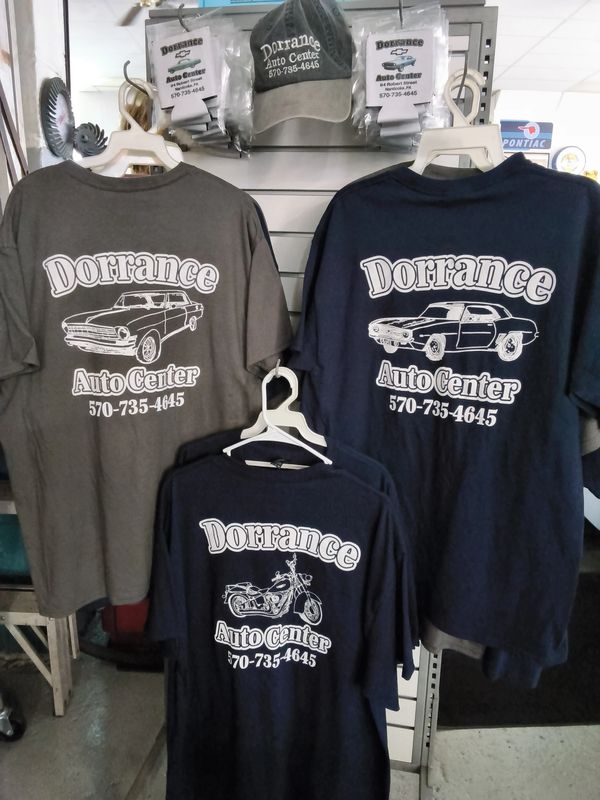 Dorrance Auto Center T-shirts and hats displayed for sale, featuring classic cars, motorcycles, and 
