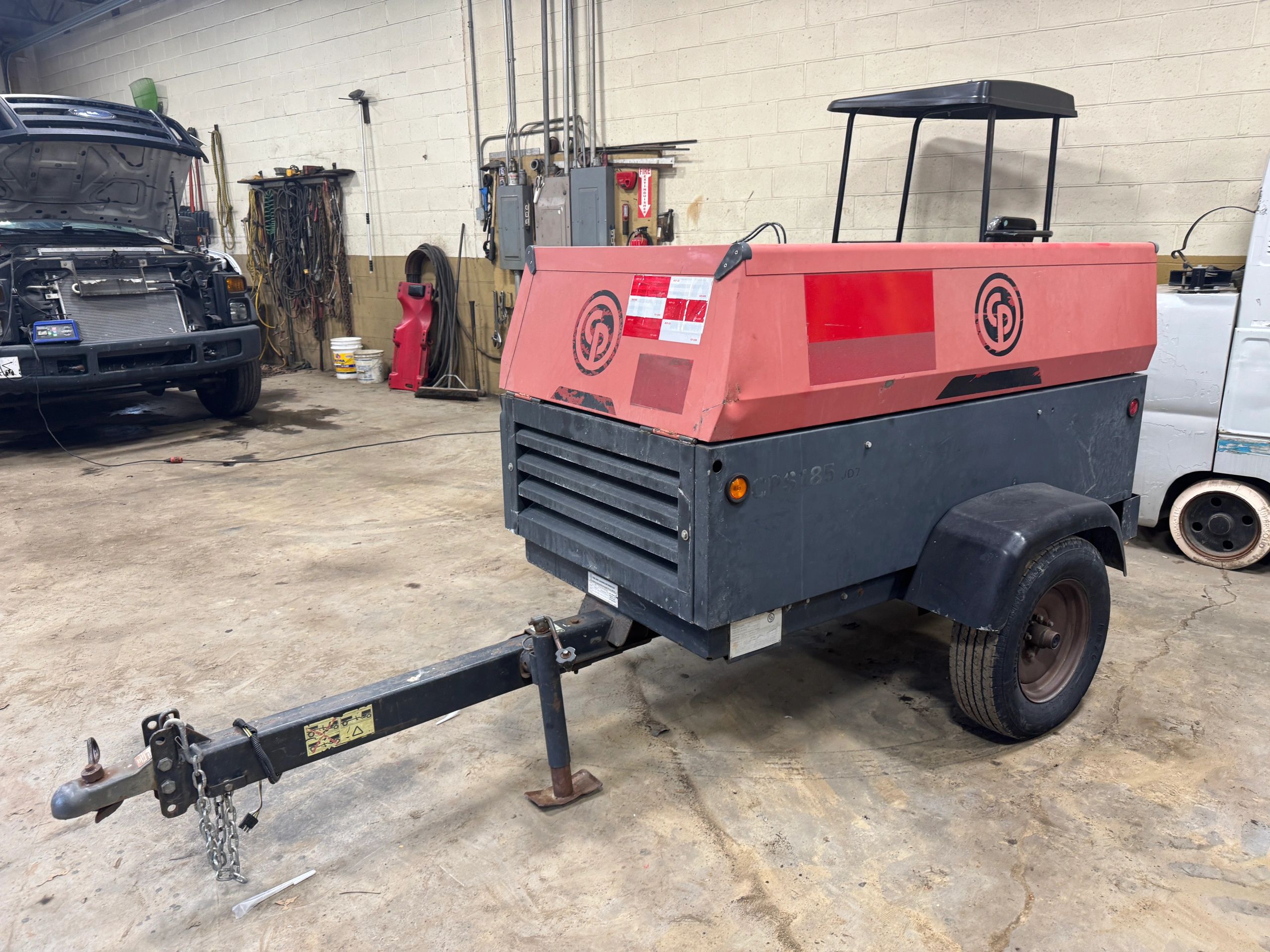 Portable air compressor with a tow hitch in a workshop.