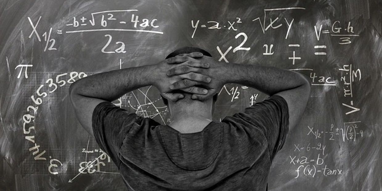 Person contemplating complex math formulas on a chalkboard.