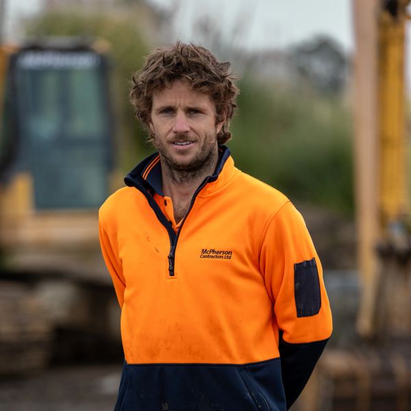 Man in orange workwear at construction site.