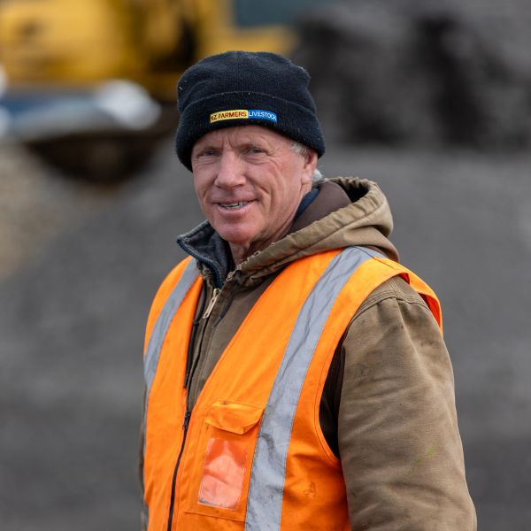 Man in an orange safety vest and black beanie outdoors.