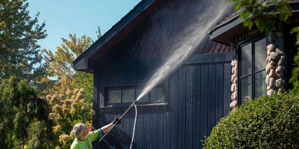 Man pressure washing gutters of home.